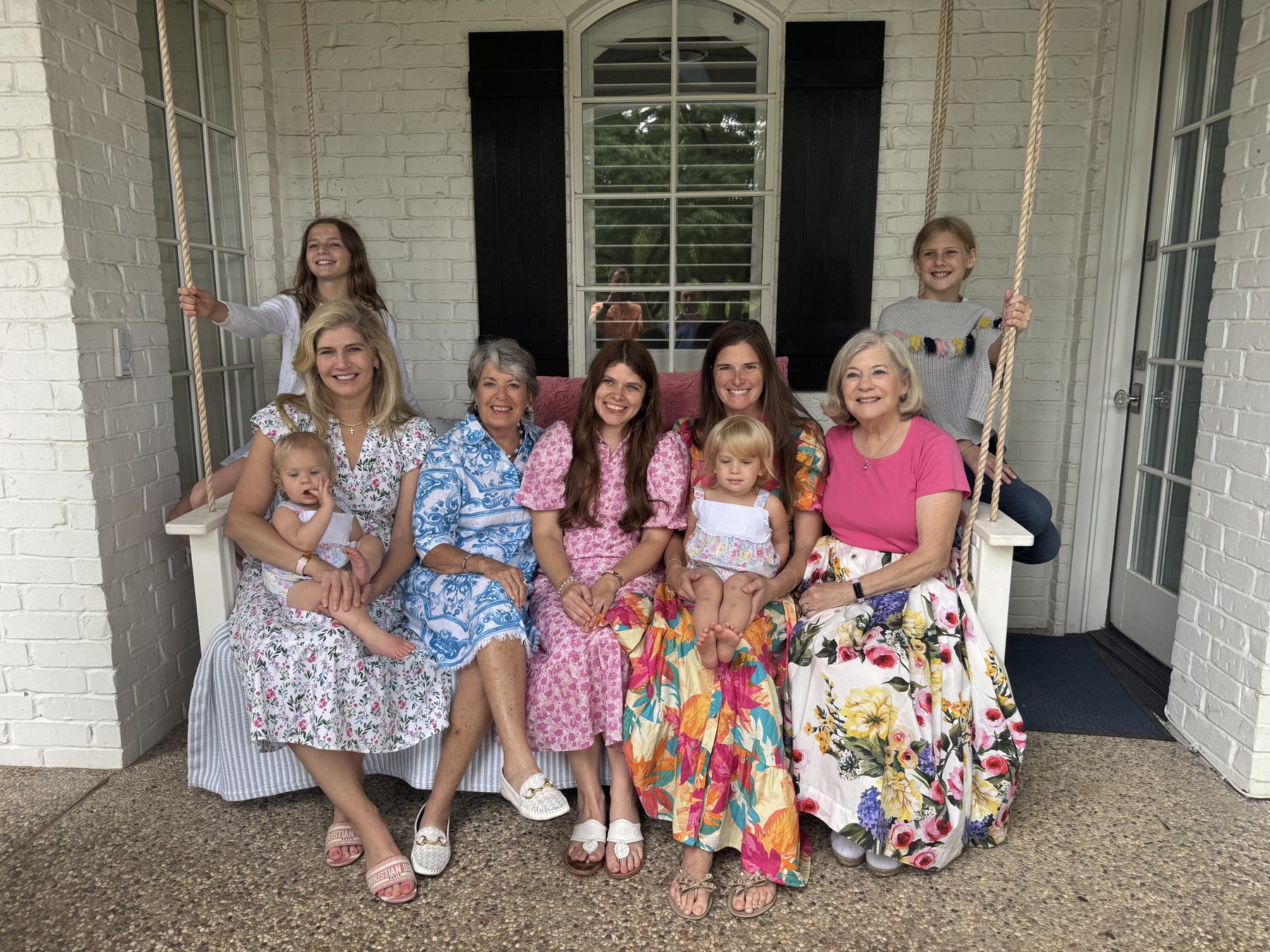 A multigenerational group of women and girls gathered on a porch