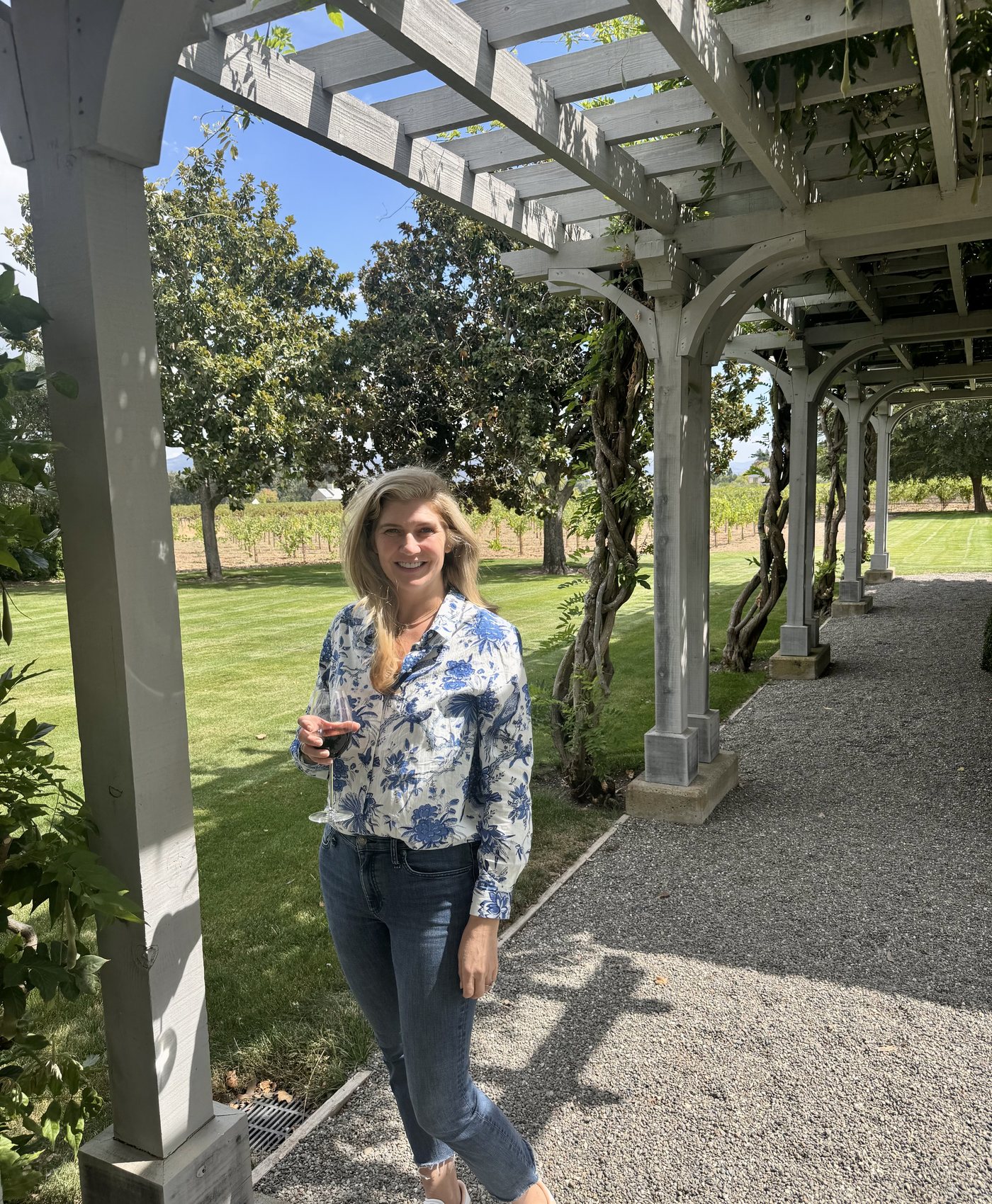 Paige smiling beneath a garden pergola