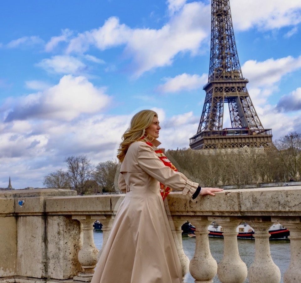 Paige beside the Eiffel Tower beneath a blue sky
